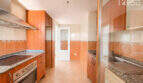 Küche der Wohnung in Llucmajor mit Holzfronten, Granitarbeitsplatten, Einbauofen und Fliesenspiegel in Orangetönen.