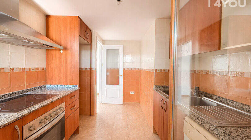 Küche der Wohnung in Llucmajor mit Holzfronten, Granitarbeitsplatten, Einbauofen und Fliesenspiegel in Orangetönen.