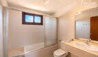 Helles Badezimmer mit Badewanne, Glasabtrennung, WC und Marmorwaschbecken im Eckreihenhaus Ses Salines