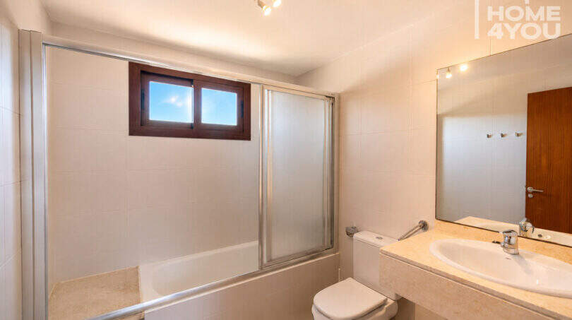 Helles Badezimmer mit Badewanne, Glasabtrennung, WC und Marmorwaschbecken im Eckreihenhaus Ses Salines