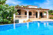 Mediterranean villa in Cala Murada with a large blue pool, arcades, and a lush garden under a blue sky.