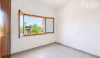 Helles leeres Zimmer mit Holzfenster und Gartenblick in Erdgeschosswohnung Cala Llombards, Fliesenboden