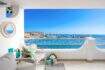 Terraza soleada del apartamento frente al mar en Port Adriano con vistas al mar, puerto y muebles de estar elegantes.