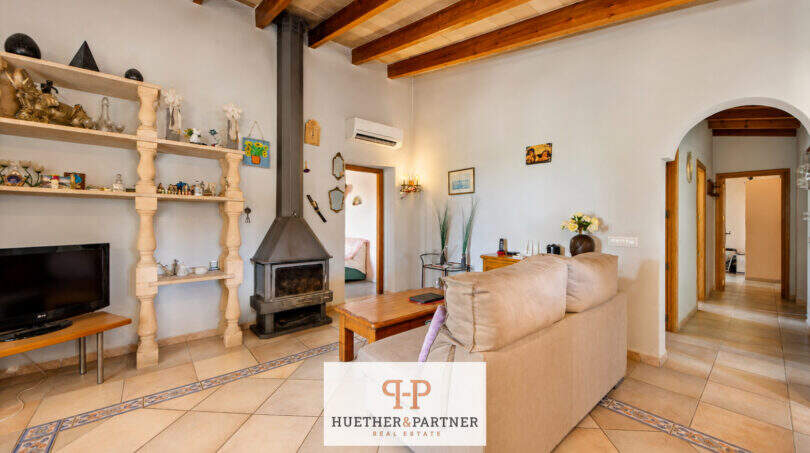 Wohnzimmer der Finca mit Holzbalkendecke, Kaminofen, Einbauregal und Klimaanlage in Felanitx