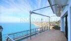Weitläufige Terrasse der Kliffvilla in Badia Blava mit Markise und spektakulärem Meerblick