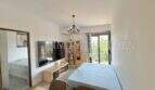 Luminoso salón con televisor, mesa de comedor, lámpara de araña, aire acondicionado y acceso a balcón con vista al mar en Palma