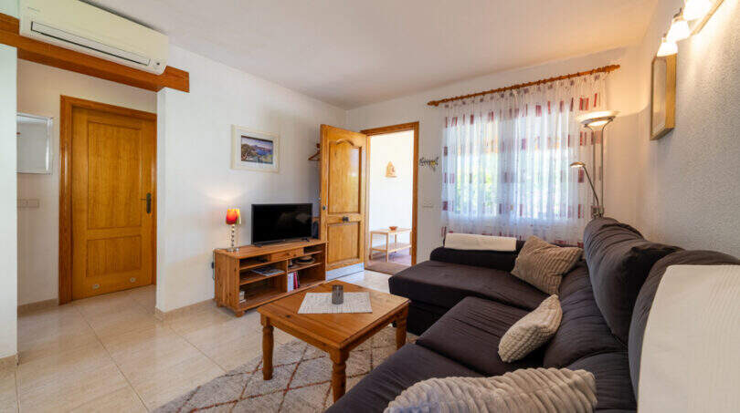Helles Wohnzimmer mit dunkelblauer Eckcouch, Holztisch, TV-Möbel und Klimaanlage in Doppelhaus Cala Murada