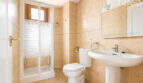 Helles Badezimmer mit Duschkabine, WC und Waschbecken, beige Fliesen, Spiegel, in 3-Zi.-Wohnung Llucmajor