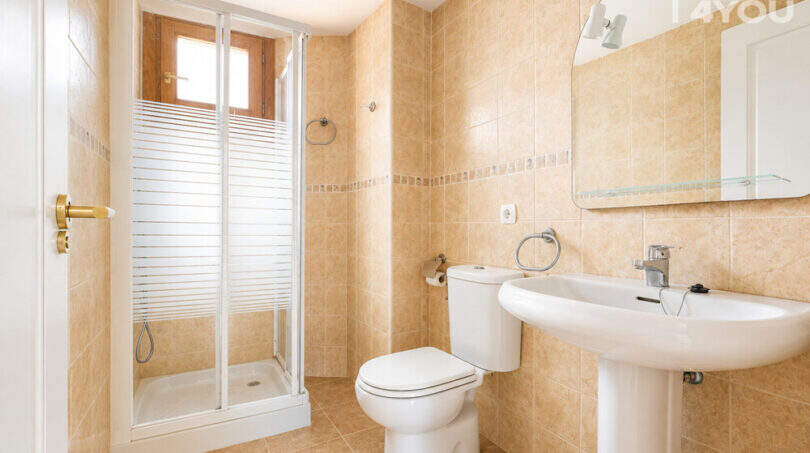 Helles Badezimmer mit Duschkabine, WC und Waschbecken, beige Fliesen, Spiegel, in 3-Zi.-Wohnung Llucmajor