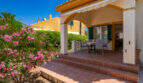 Überdachte Terrasse mit Esstisch, Terrakottafliesen und blühendem Oleander in Cala Murada