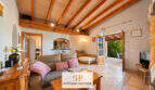 Helles Wohnzimmer der Finca Felanitx mit Holzbalkendecke, Sofa und Zugang zur sonnigen Terrasse