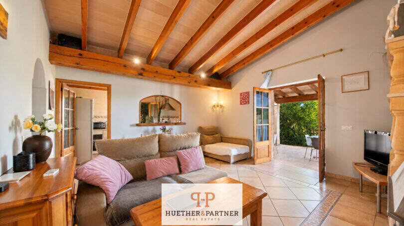 Helles Wohnzimmer der Finca Felanitx mit Holzbalkendecke, Sofa und Zugang zur sonnigen Terrasse