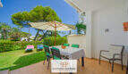 Sonnige Terrasse mit Esstisch und Sonnenschirm, Blick auf gepflegten Garten mit Liegestühlen, Cala d'Or