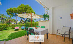 Sonnige Terrasse mit Esstisch und Sonnenschirm, Blick auf gepflegten Garten mit Liegestühlen, Cala d'Or