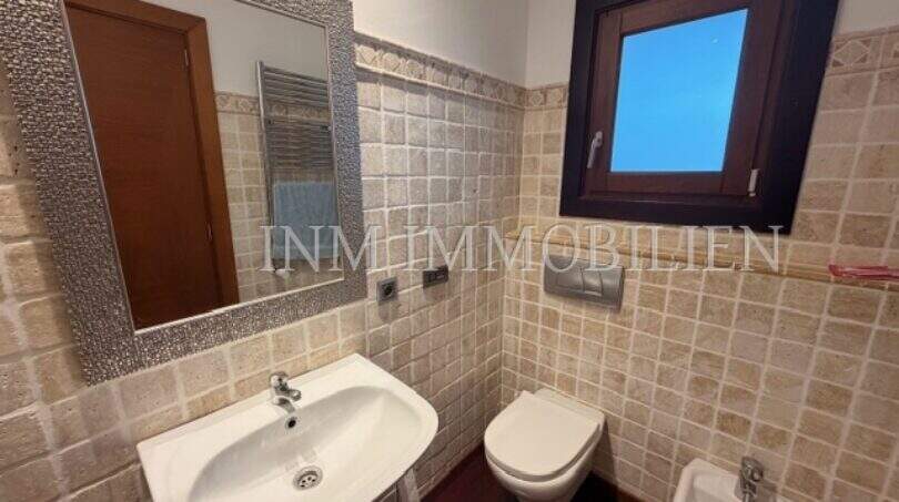 Badezimmer der Villa mit Wandtoilette, Bidet, Waschbecken, Mosaikspiegel und Natursteinfliesen in Marratxí.