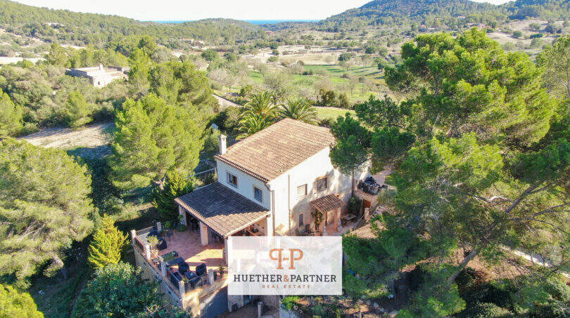 Luftaufnahme einer mediterranen Finca in Son Macià, umgeben von Pinien, mit Terrasse und Blick ins grüne Tal.