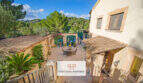 Mediterraner Innenhof der Finca Son Macià mit Terrasse, Naturstein und üppigem Grün im Hintergrund