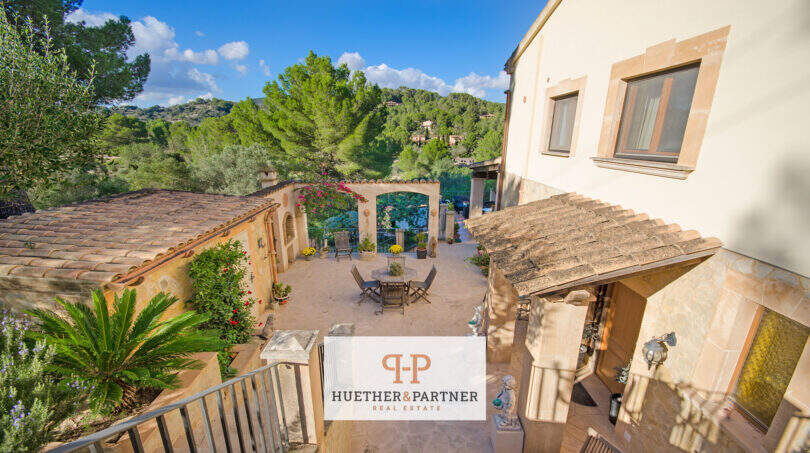 Mediterraner Innenhof der Finca Son Macià mit Terrasse, Naturstein und üppigem Grün im Hintergrund