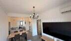 Luminoso salón con gran televisor, mesa de comedor y lámpara de araña en apartamento renovado en Palma