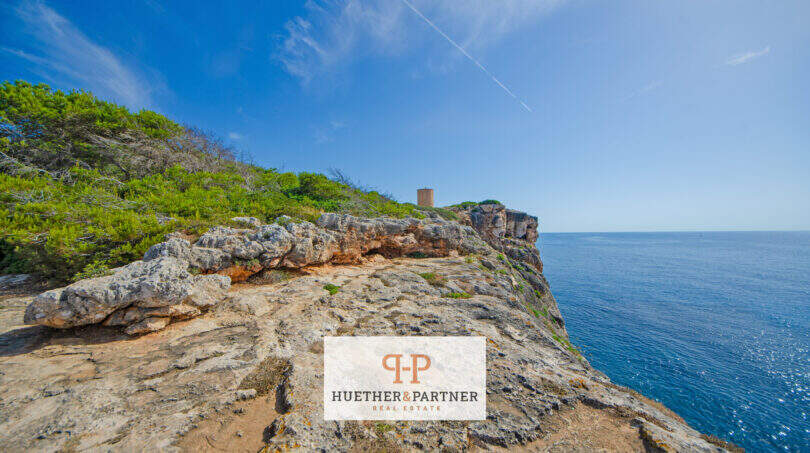 Felsklippe mit Wachturm direkt am Meer in Porto Cristo, 1. Meereslinie, blauer Himmel und Mittelmeer