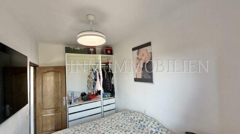 Luminoso dormitorio del apartamento en Palma con cama doble, armario abierto y ventilador de techo.