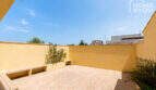 Sonnige Dachterrasse mit Natursteinboden, gelben Mauern und Bepflanzung des Eckreihenhauses in Ses Salines.