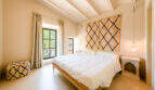 Helles Schlafzimmer der Finca in Esporles mit Holzbett, Berber-Wandteppichen und mediterranem Charme.