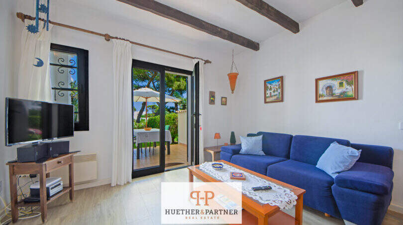 Helles Wohnzimmer mit blauem Sofa, Holzbalken und Terrassentür zum Außenbereich in Cala d'Or