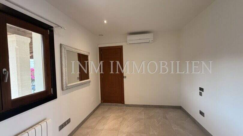 Habitación luminosa y vacía con aire acondicionado, radiador, suelo de mármol y ventana con vista al jardín en villa Marratxí