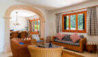 Luminoso salón de la villa familiar de Cala Murada, con muebles de ratán, un arco de medio punto y vistas al comedor.