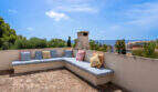 Terraza en la azotea con un banco en forma de L, cojines de colores y vistas al mar en Villa Cala Murada