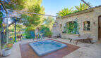 Sonnige Terrasse der Finca Son Macià mit eingelassenem Jacuzzi, Natursteinmauer und Liegestühlen