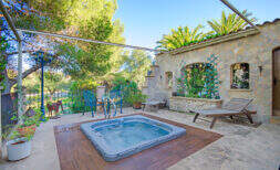 Sonnige Terrasse der Finca Son Macià mit eingelassenem Jacuzzi, Natursteinmauer und Liegestühlen