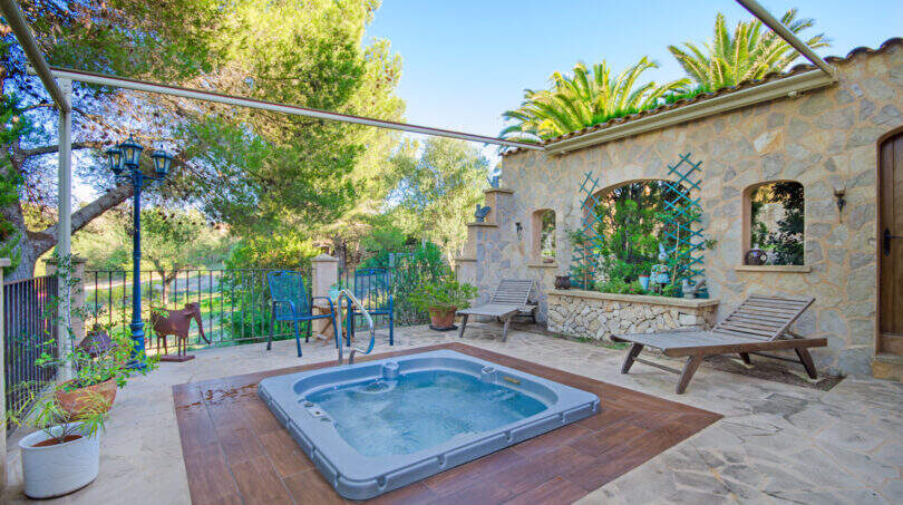 Sonnige Terrasse der Finca Son Macià mit eingelassenem Jacuzzi, Natursteinmauer und Liegestühlen