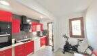 Cocina moderna con frentes rojos de alto brillo, electrodomésticos integrados y área deportiva en apartamento renovado en Palma