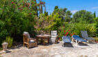 Sonnenterrasse mit Liegestühlen und Sitzgruppe, umgeben von üppigem mediterranem Garten in Cala Murada.