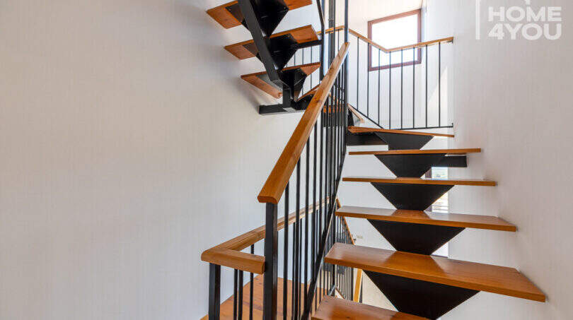 Moderne Treppe mit Holzstufen und schwarzem Metallgeländer im Eckreihenhaus Ses Salines