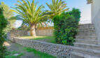Gepflegter Garten der Finca Son Macià mit Palmen, Natursteinmauern und Treppenaufgang zur Terrasse