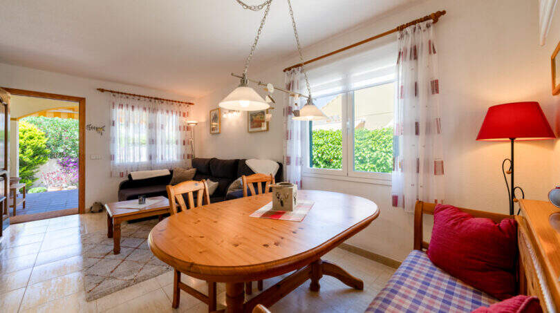 Helles Wohn-Esszimmer mit Holztisch, gemütlicher Sitzecke und Gartenblick im Doppelhaus Cala Murada