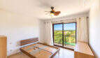 Helles Schlafzimmer mit Holzbett, Deckenventilator und Balkon mit Meerblick im Eckreihenhaus Ses Salines