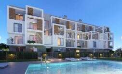 Vista exterior de nueva construcción Palmanova: complejo residencial moderno con piscina, balcones y elementos de madera en la luz del atardecer.