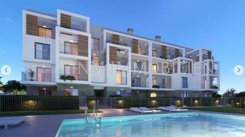 Exterior view of new construction Palmanova: modern residential complex with pool, balconies and wood elements in evening light.