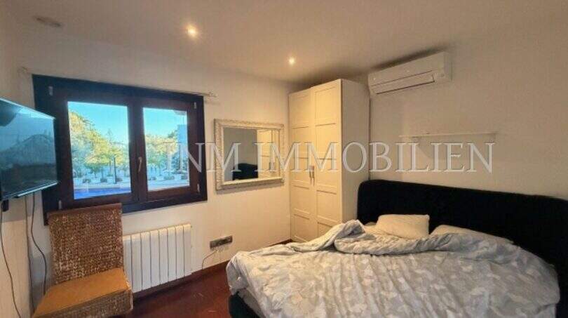 Helles Schlafzimmer der Gästewohnung in Villa Marratxí mit Doppelbett, Klimaanlage und Fenster zum Garten.