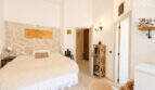 Helles Schlafzimmer mit Steinwand, Doppelbett und rustikalem Charme in historischer Wohnung Ses Salines
