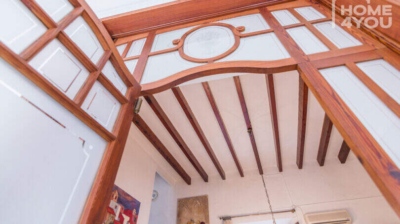Historisches Herrenhaus in Porreres: Eleganter Holzbogen mit Glasfeldern und freiliegende Holzbalkendecke im Durchgang