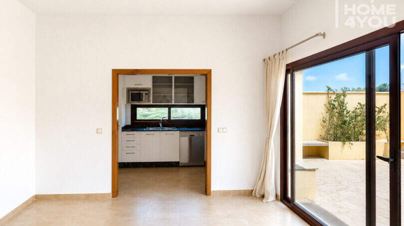 Helles Wohnzimmer mit Blick in moderne Küche und Zugang zur Terrasse, Eckreihenhaus Ses Salines