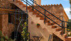 Mediterraner Innenhof mit Außentreppe, Schmiedeeisen-Geländer und Terrakotta-Fassade des Agroturismo bei Ses Salines