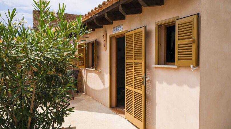 Mediterranes Landhaus mit goldenen Holzläden, Terrakotta-Dach und Innenhof des Agroturismo bei Ses Salines