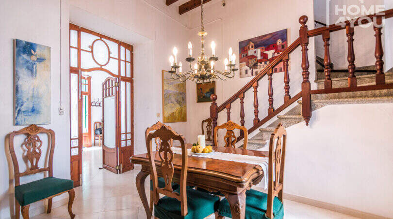 Elegantes Esszimmer mit antikem Holztisch, grünen Polsterstühlen, Lüster & historischer Holztreppe im Herrenhaus Porreres