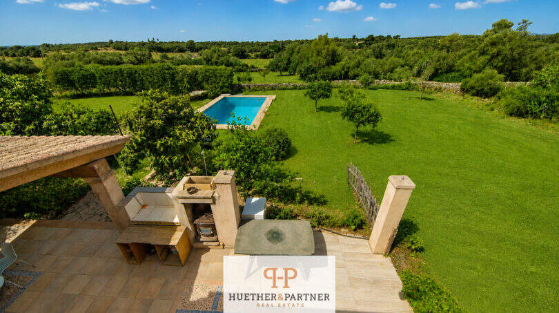 Luftaufnahme Finca Felanitx: Terrasse mit Sitzbereich, rechteckiger Pool und weitläufiger Garten mit Obstbäumen